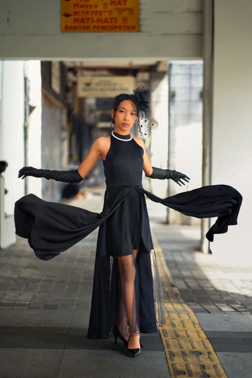 Free Young woman in stylish black dress posing in an urban alleyway in Bandung, Indonesia. Stock Photo