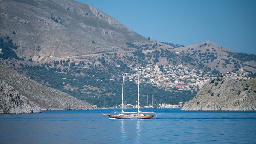 Free Beautiful coastal scene featuring a sailing yacht against mountainous backdrop. Stock Photo