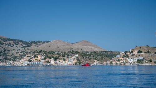Free A picturesque view of Symi Island harbor with colorful buildings and clear blue water. Stock Photo