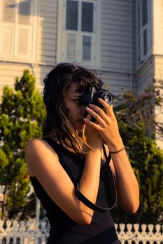 Woman photographer capturing an outdoor scene with a classic camera.
