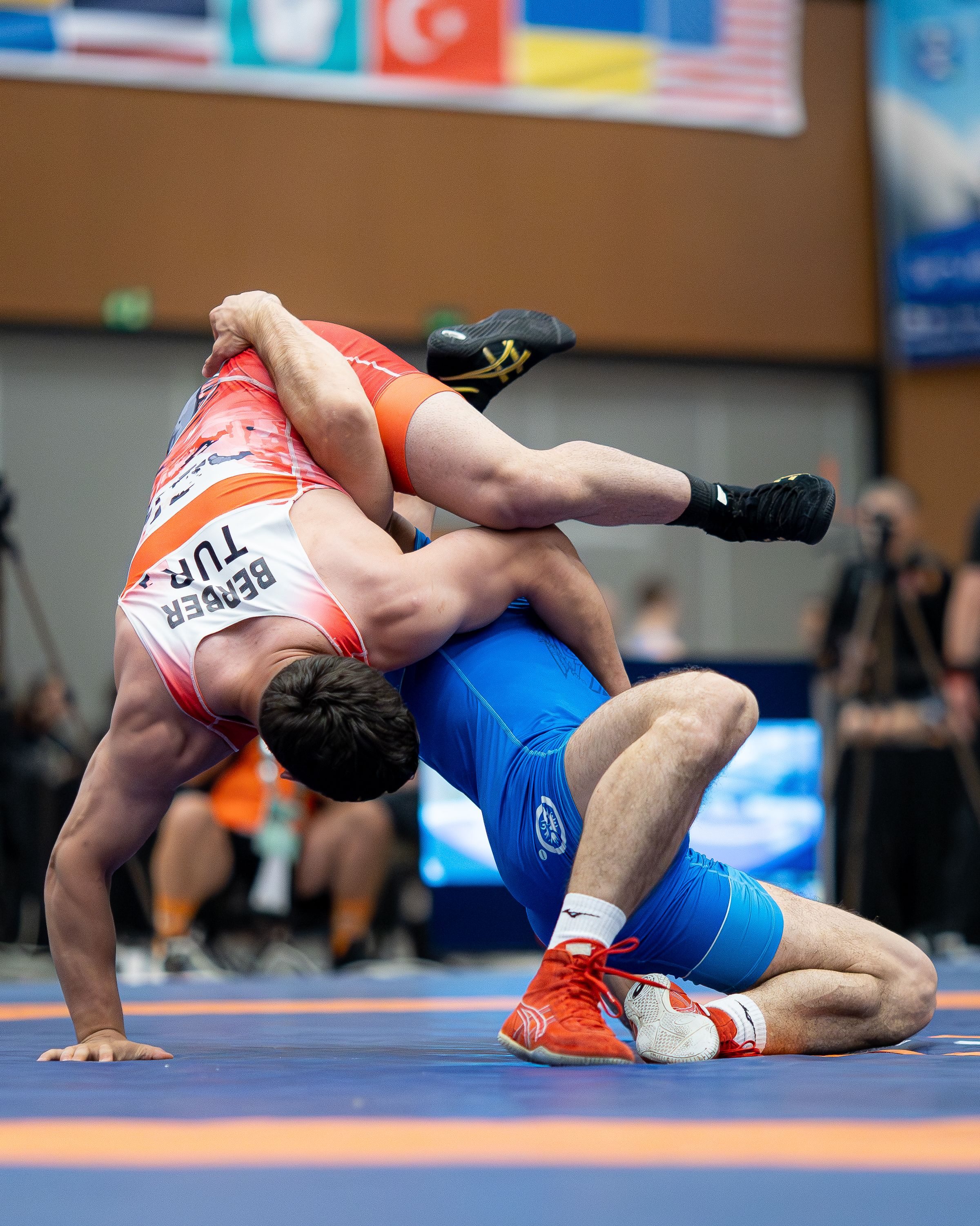 Intense wrestling match captured mid-action in an indoor arena, showcasing sport's athleticism.