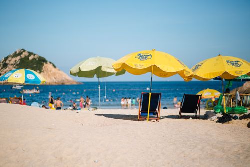 Free A scenic beach view featuring vibrant umbrellas and people enjoying the seaside. Stock Photo