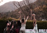 Elegant bride tossing bouquet to unmarried girlfriends on celebration of wedding in garden