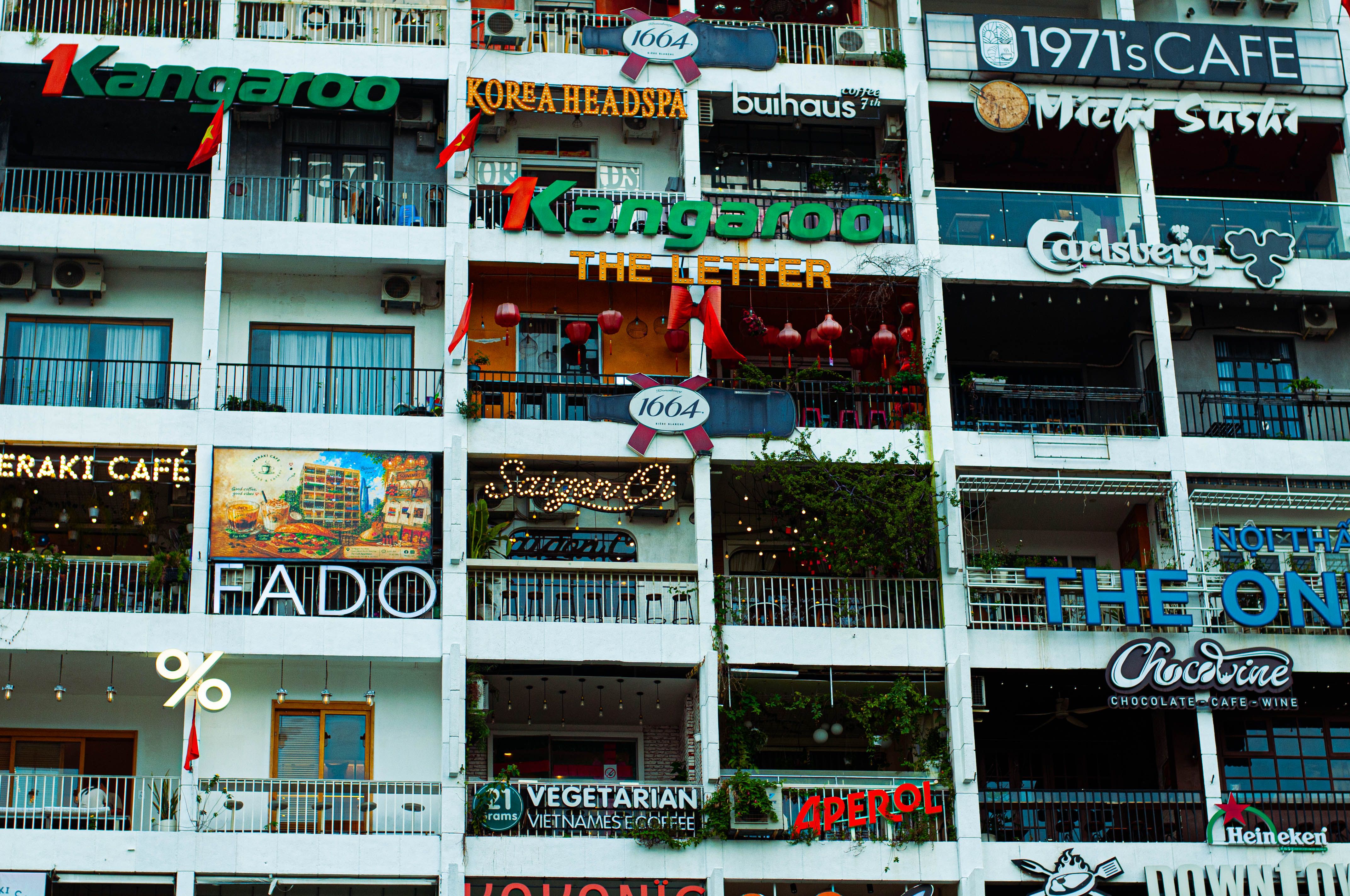 Colorful cafe and restaurant signs on a multi-story urban building facade, creating a vibrant city atmosphere.