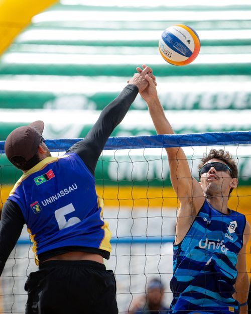 Free Two male players compete in an exciting beach volleyball match in Brazil, showing athletic skill. Stock Photo