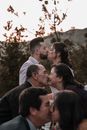 Elegant ethnic newlyweds and parents kissing on wedding day outdoors