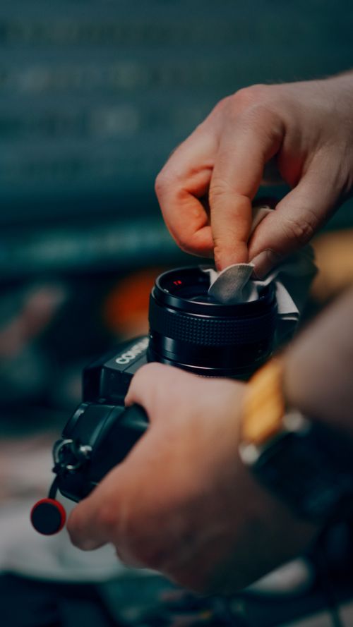 Free Close-up of hands meticulously cleaning a vintage camera lens using a cloth. Stock Photo