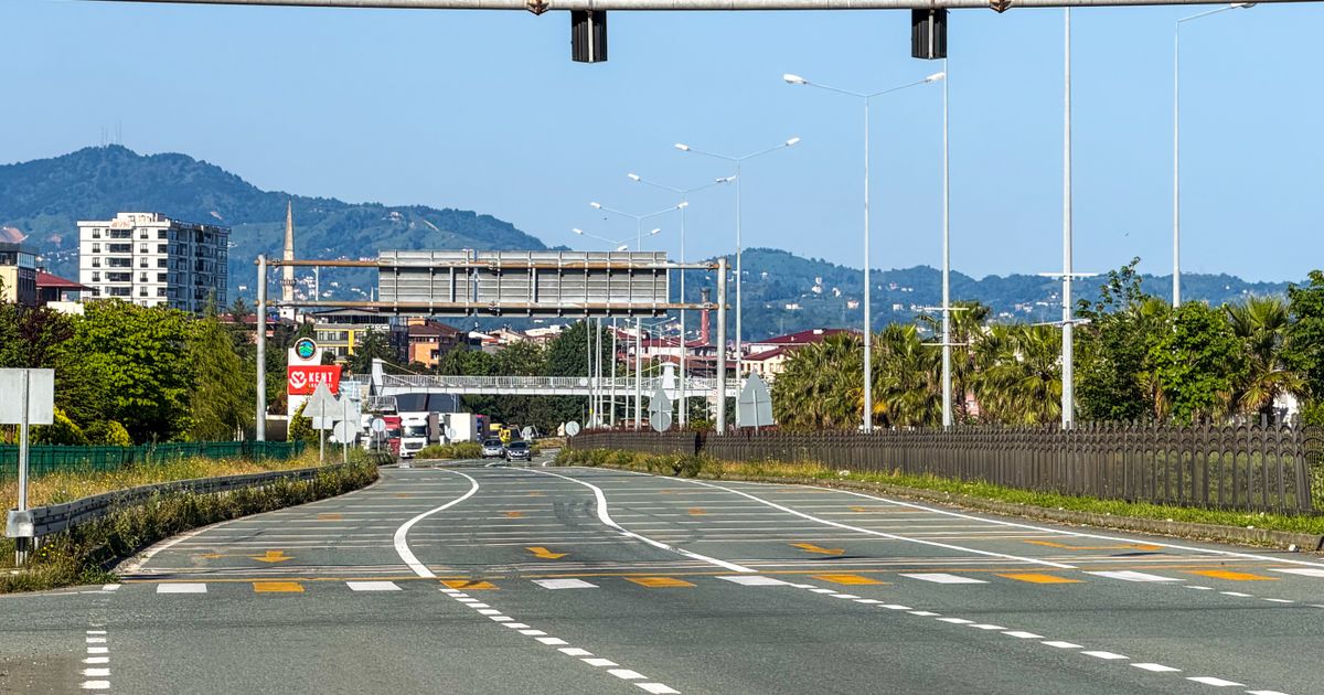 Vista de uma rua vazia da cidade com semáforos e montanhas, perfeita para temas urbanos e de viagem.