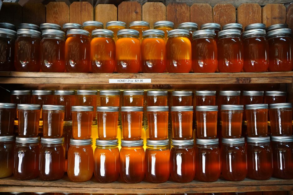 Dozens of honey jars on shelves in a rustic setting create a warm, inviting display. - The Benefits of Buying Organic and Natural Products