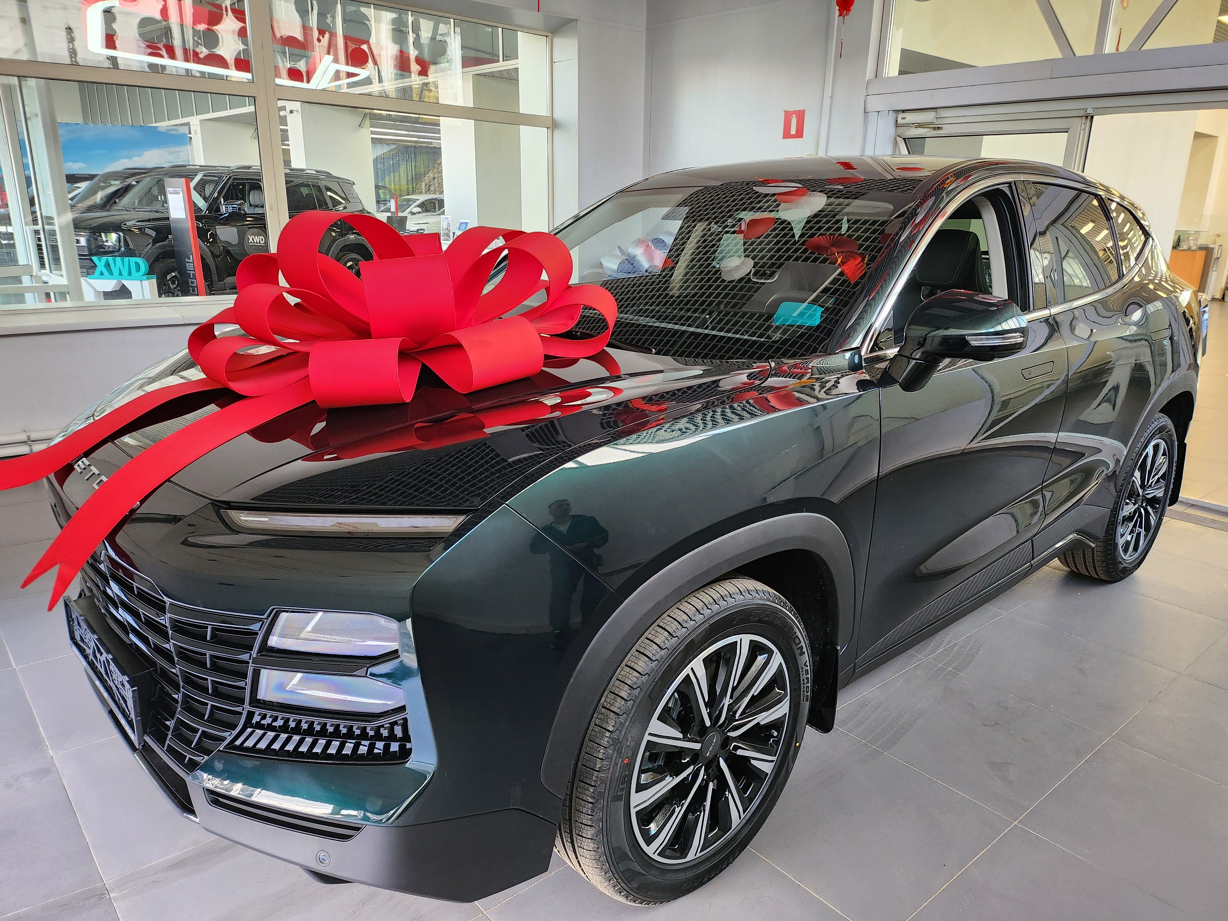 A new car with a large red bow on display in a showroom