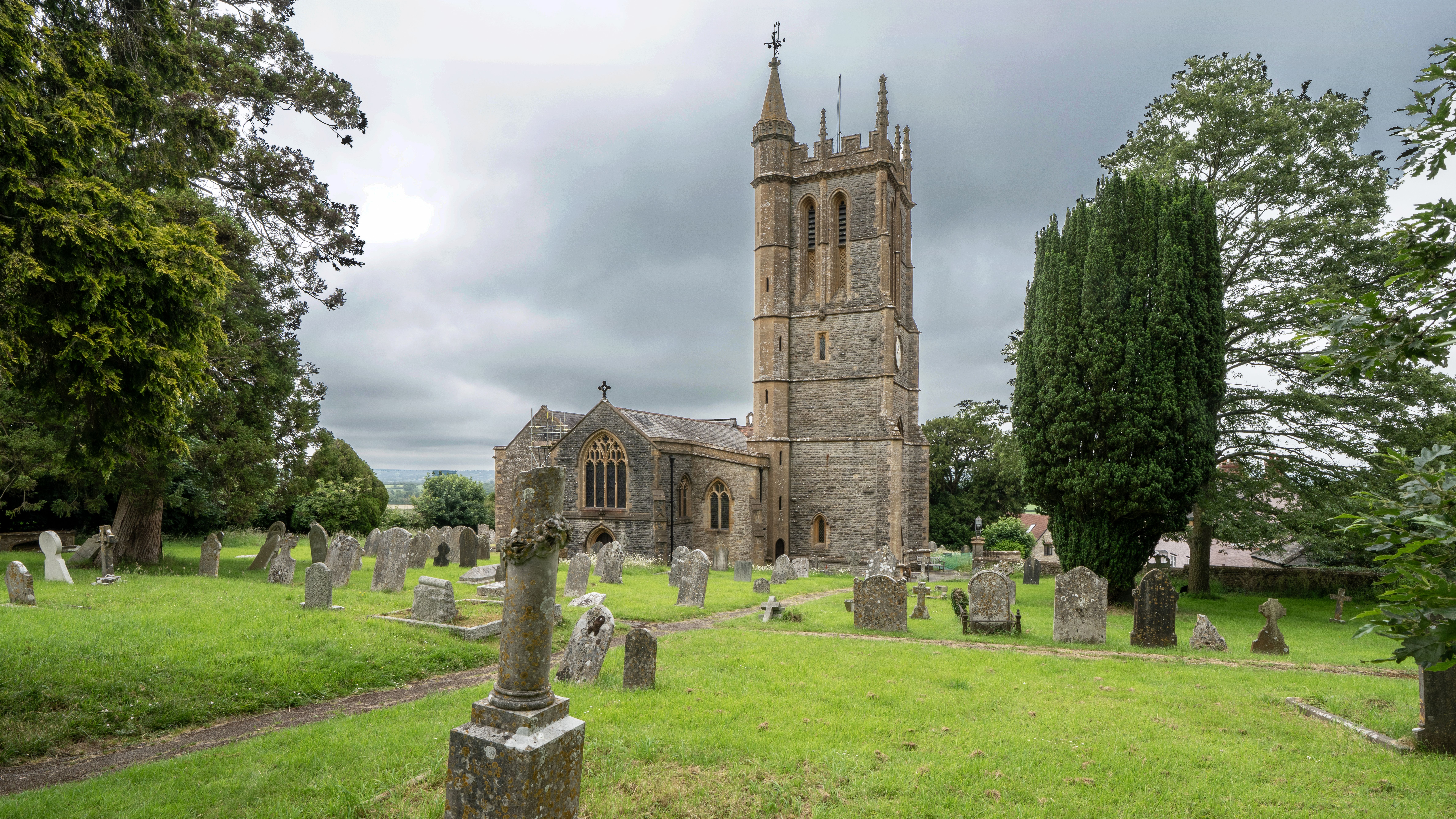 A picturesque English church and graveyard under a cloudy sky in Stalbridge, UK, showcasing stone architecture.