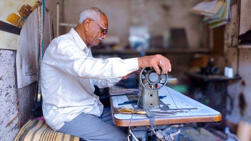 Free A senior tailor in Jodhpur expertly works with a vintage sewing machine, showcasing traditional craftsmanship. Stock Photo