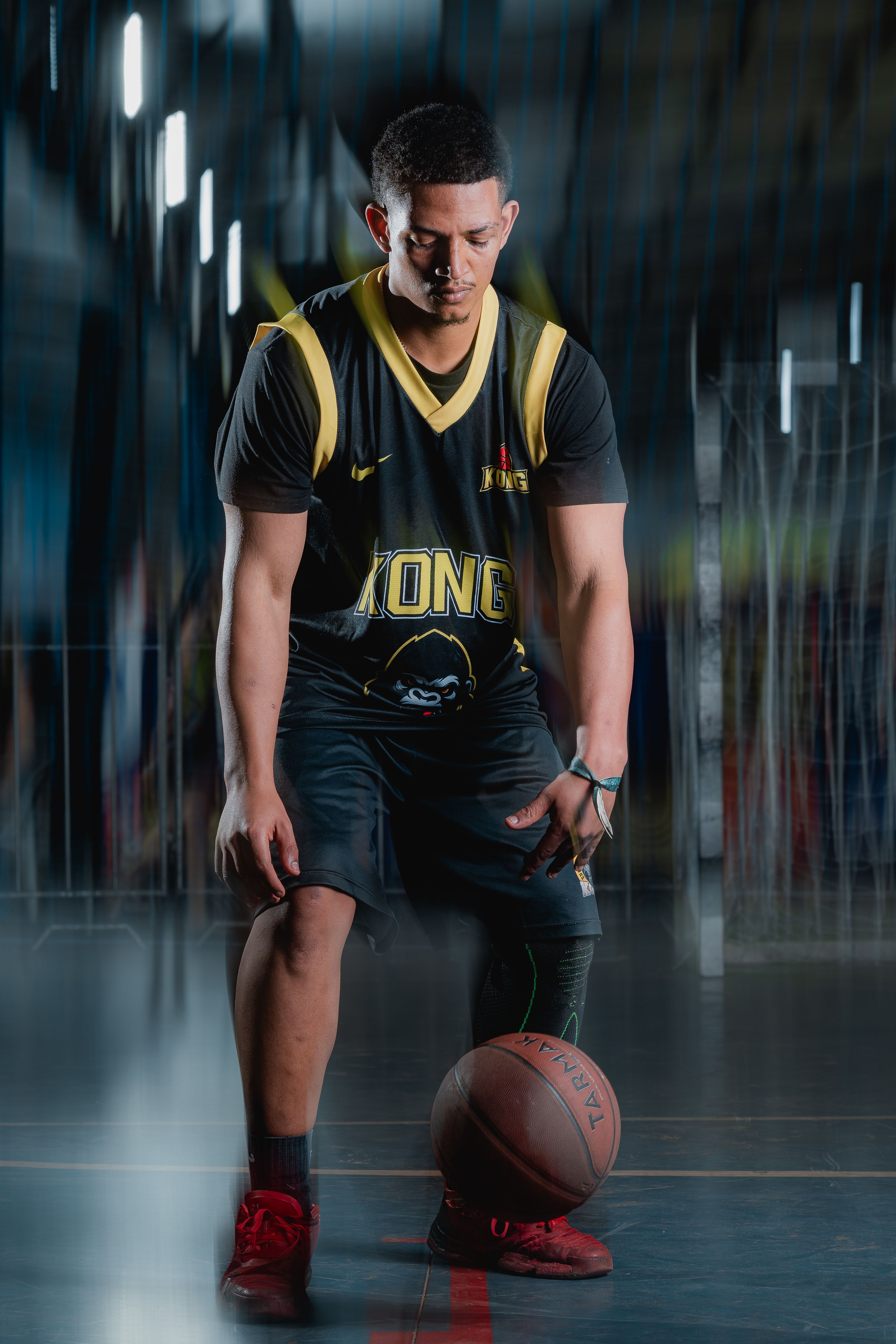 Focused young male athlete dribbling a basketball indoors, showcasing skills and determination.