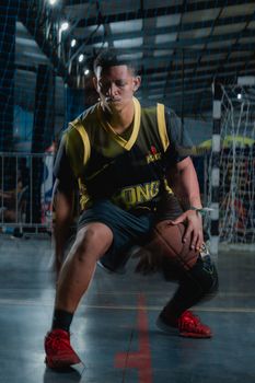 A dynamic image of a male basketball player dribbling on an indoor court, showcasing intense focus and movement.