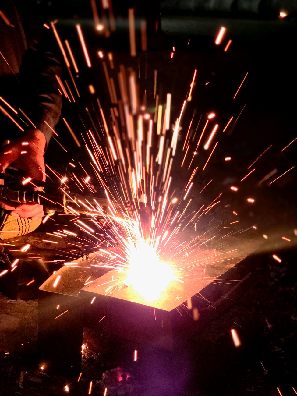 Captivating night welding scene in Sialkot with bright sparks flying against the dark backdrop.