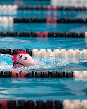 Child swimming in a pool wearing a whimsical swim cap, perfect for aquatic activities.