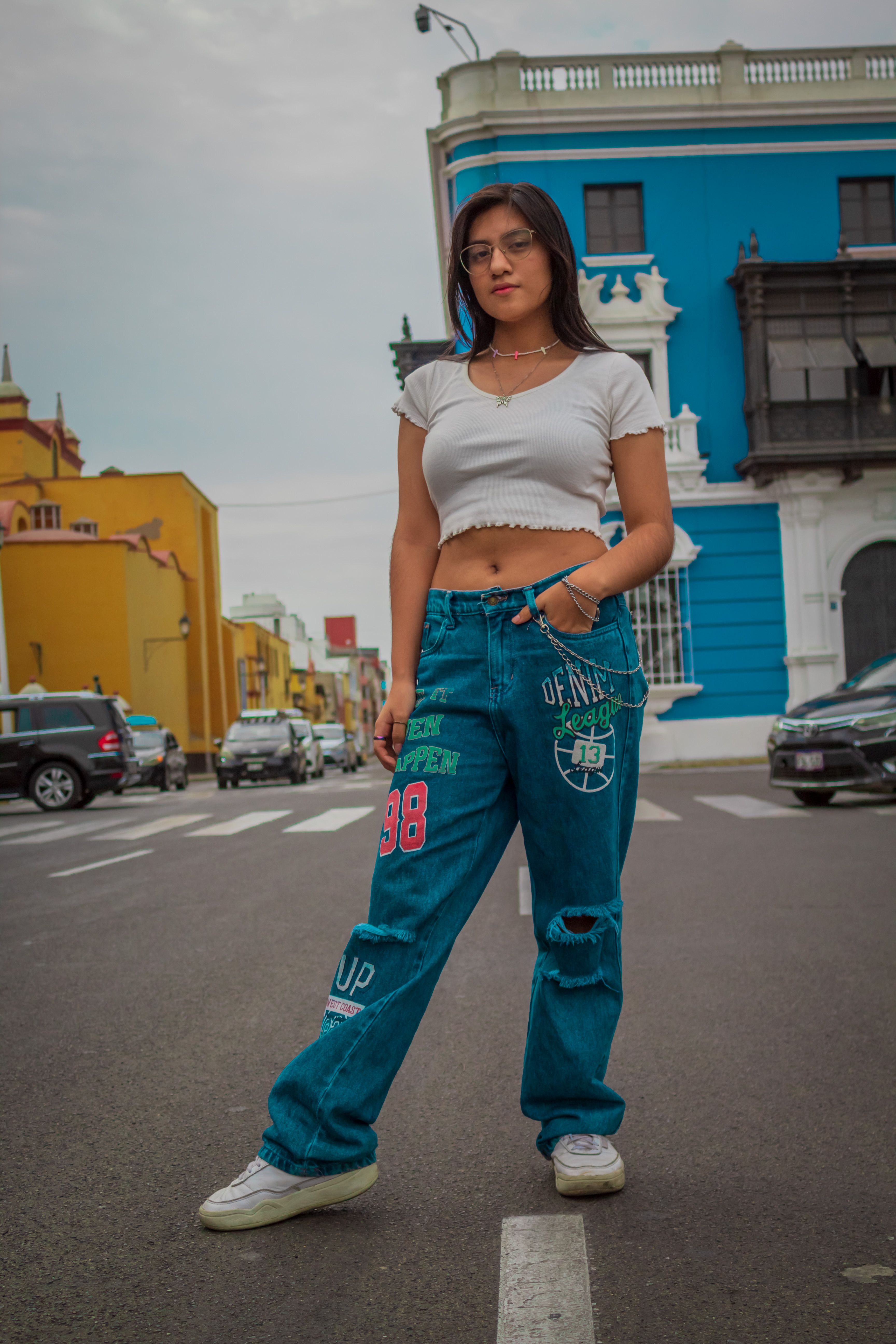 Young woman in fashionable jeans poses on a vibrant street in Trujillo, Peru.