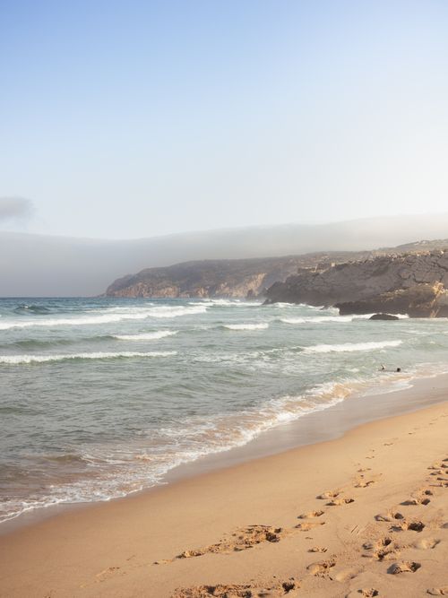 Free Breathtaking view of Praia Grande beach with waves crashing against the sandy shore in Sintra, Portugal. Stock Photo
