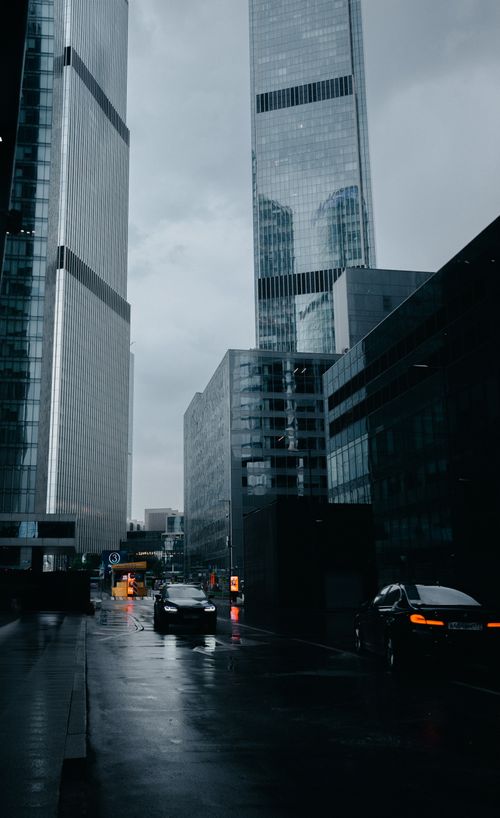 Free Urban scene with tall skyscrapers, rainy street, and moving cars during daytime. Stock Photo