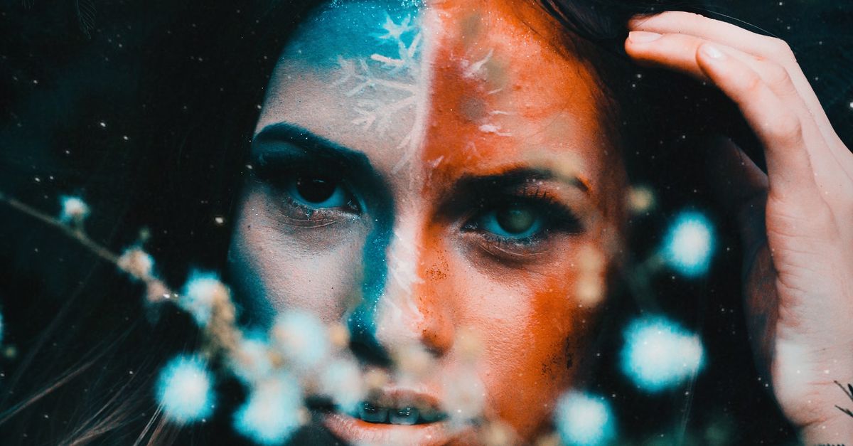 Emotionless woman with painted face standing near blooming flowers