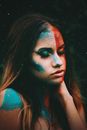 Calm woman with bright painted face sitting with closed eyes