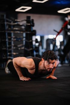 Focused man doing push-ups on a gym floor, showcasing strength and fitness.
