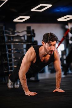 A muscular man performing push-ups in a modern gym, demonstrating strength and fitness.