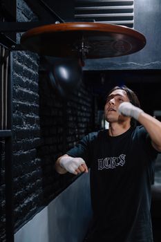 A young male boxer practicing on a speed bag indoors, enhancing focus and agility.