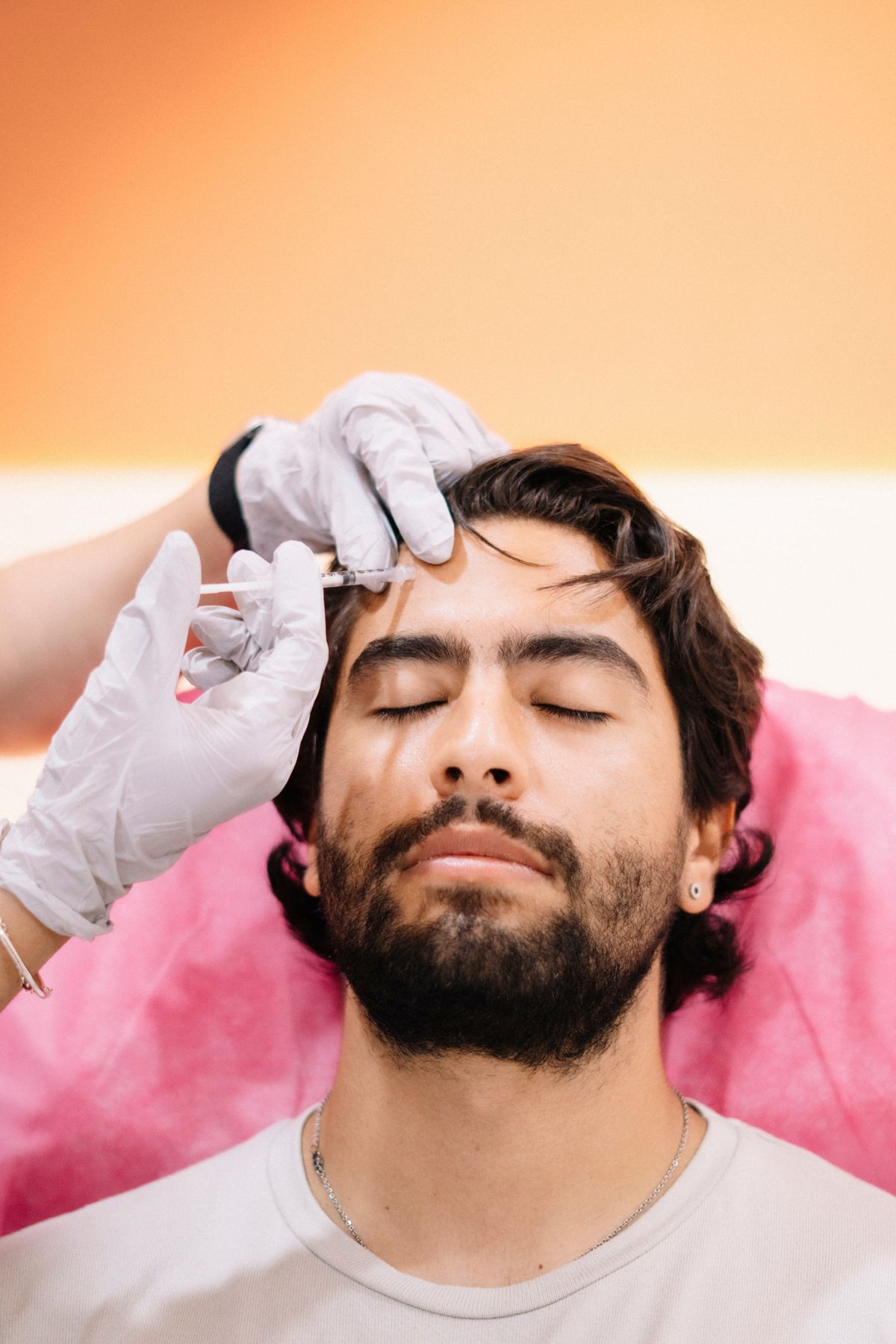 Male patient receiving an injectable forehead treatment in a clinic.