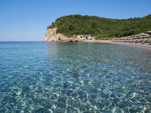 Free Serene beach with clear water and scenic cliffs under a bright blue sky. Stock Photo