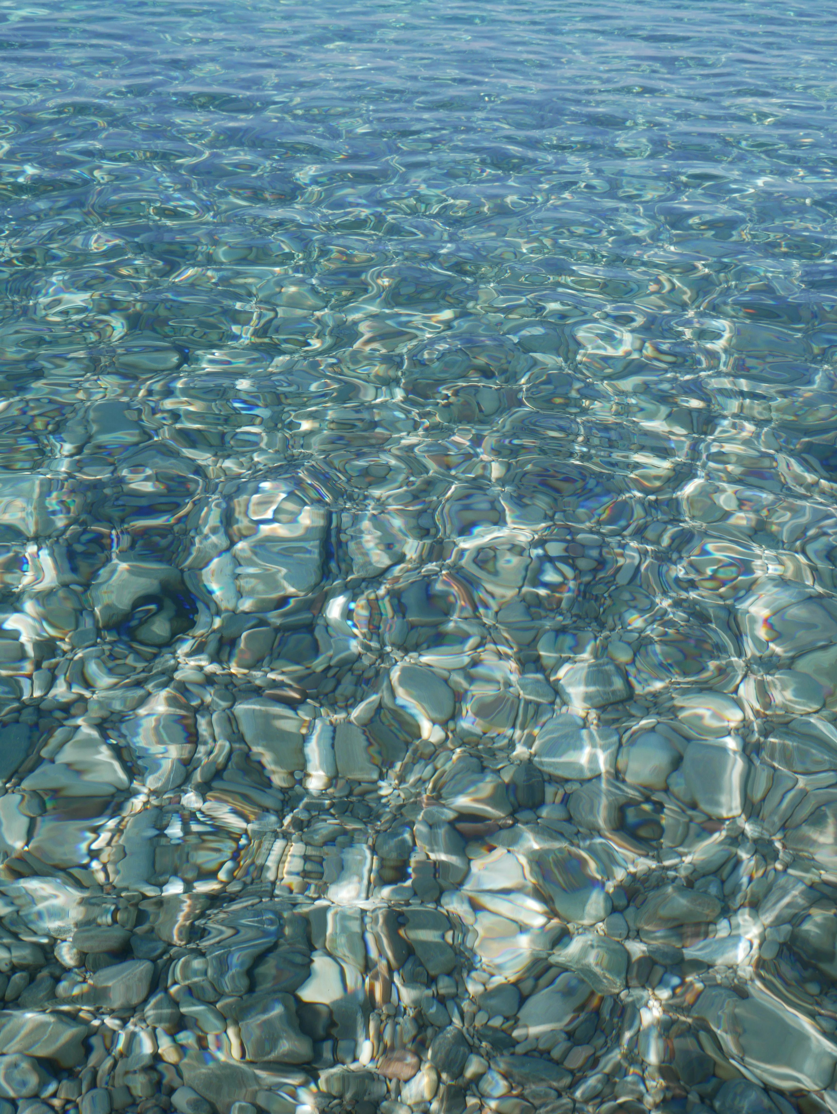 Rippling clear water above pebbles creates a mesmerizing natural pattern.