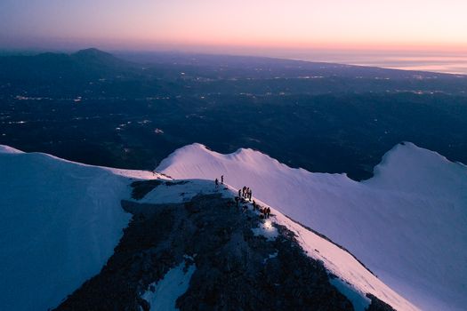Aerial view of Gran Sasso peak at twilight with silhouettes of people enjoying the magnificent mountain panorama.