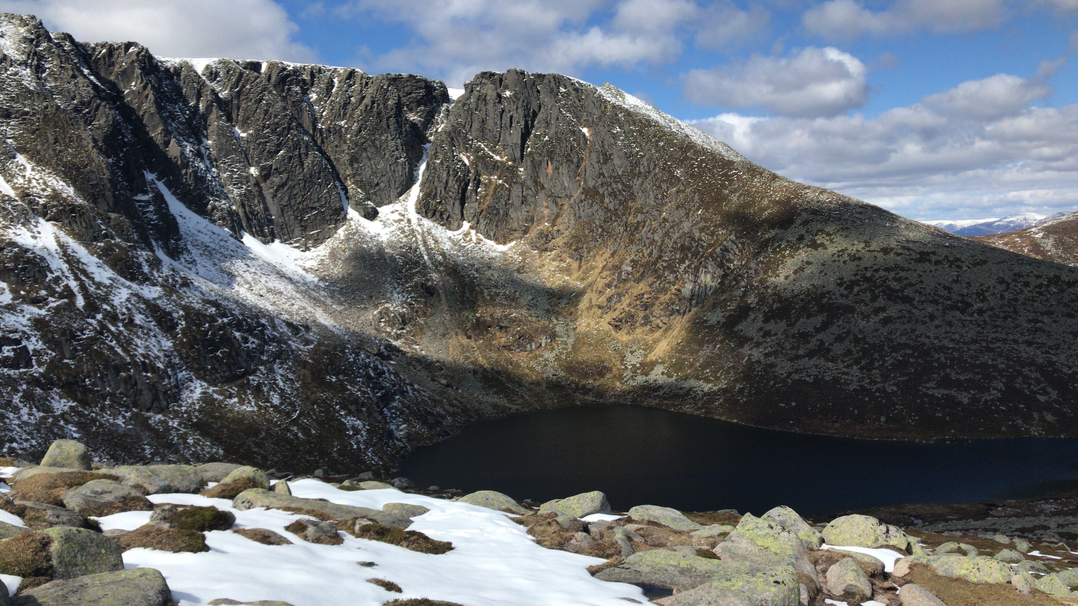 Snow lying in the corrie above a dark Highland loch