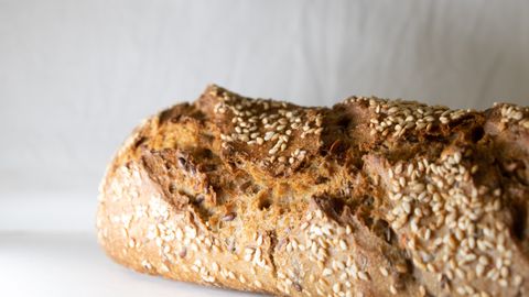 Freshly baked homemade bread loaf with sesame seeds, highlighting texture and crust.