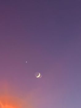 A stunning crescent moon and bright star captured against a colorful twilight sky.