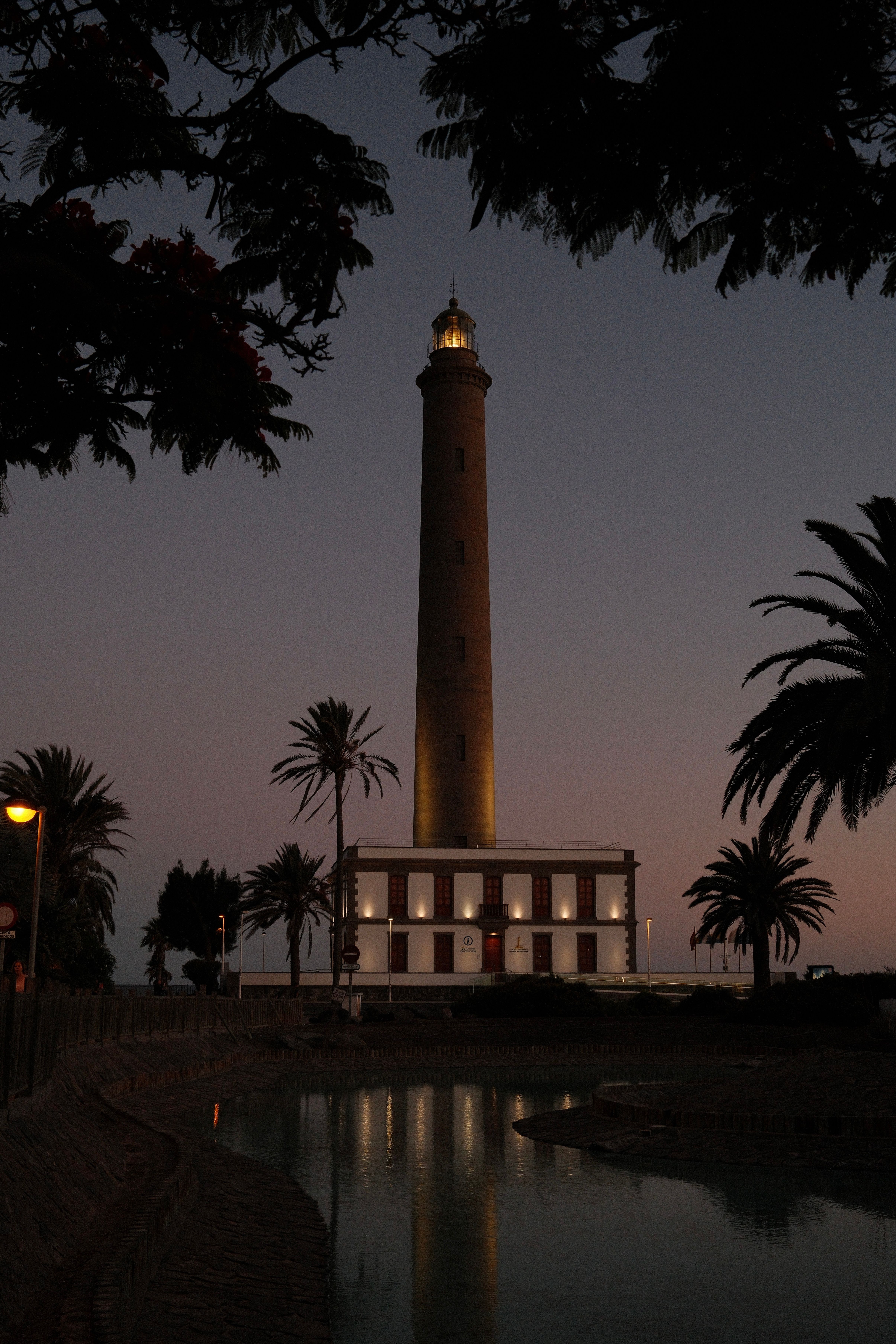 Twilight view of Maspalomas Lighthouse surrounded by palms in Gran Canaria, Spain.