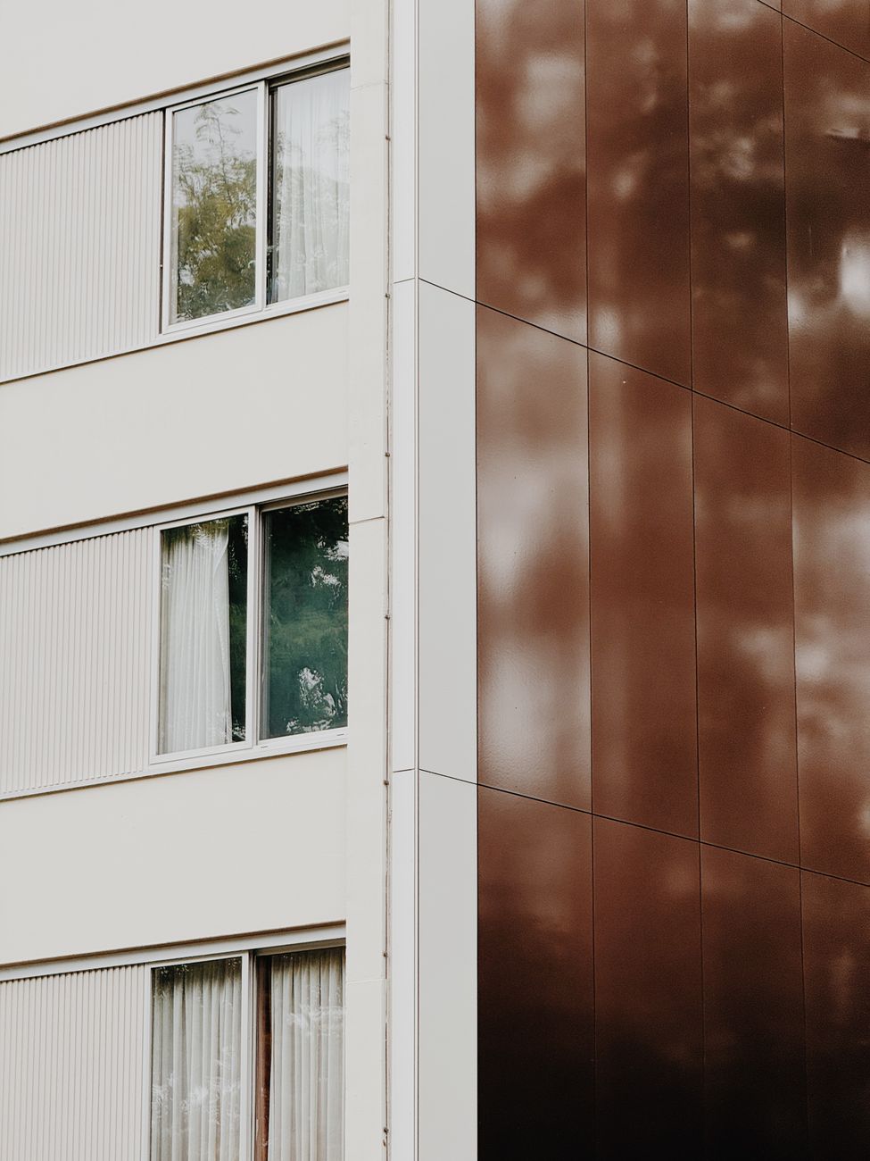 A close-up view of a modern building facade with reflective paneling and windows.