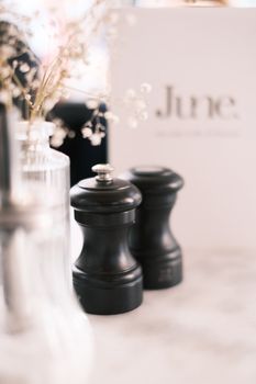 A soft-focus table setting featuring elegant black pepper mills and delicate flowers.
