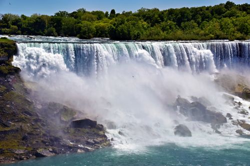 Free Breathtaking view of Niagara Falls captured in vibrant summer sunlight with lush green surroundings. Stock Photo