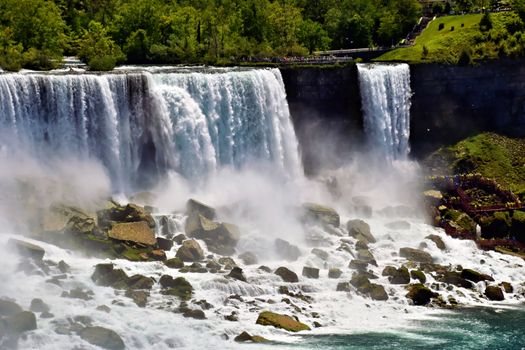Stunning summer view of the majestic Niagara Falls in Ontario, Canada, showcasing cascading water and vibrant greenery.