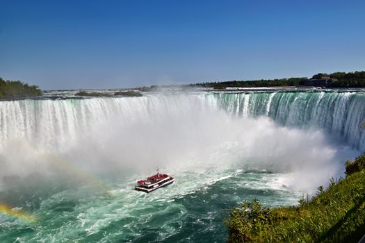 A breathtaking shot of Niagara Falls, Ontario with a tour boat navigating the waters.