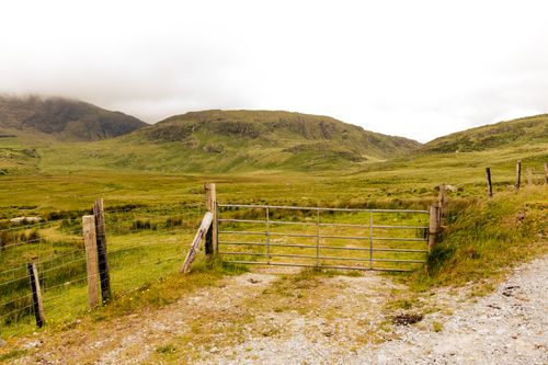 Free A rustic metal gate opens to scenic rolling hills in Fortuna, Spain, surrounded by lush greenery. Stock Photo