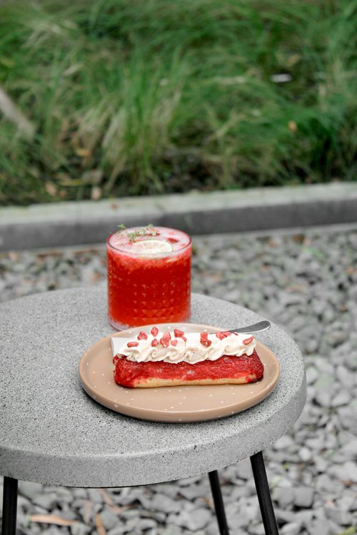 Free Outdoor setting with a raspberry tart with cream and a refreshing drink on a grey table. Stock Photo