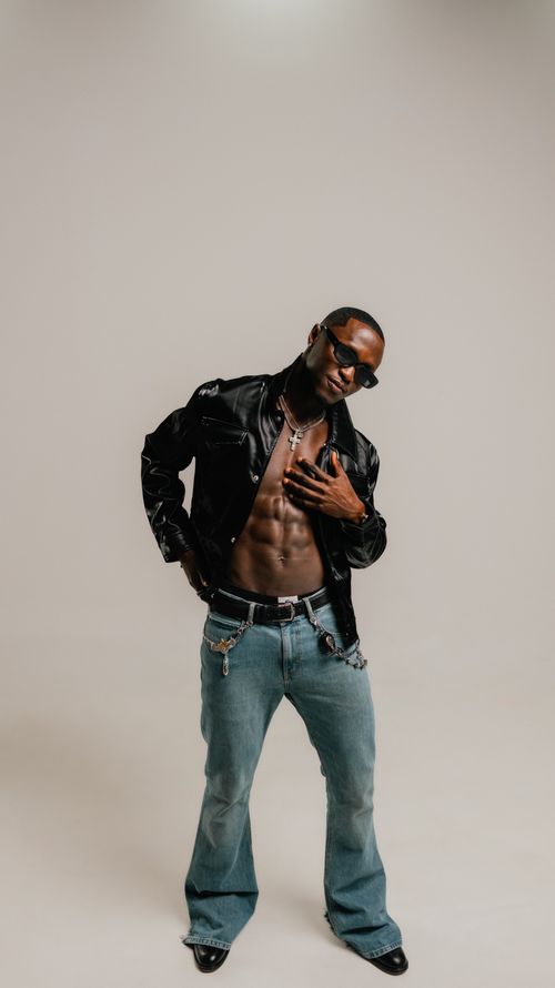 Free Stylish man posing confidently with leather jacket and sunglasses in studio setting. Stock Photo