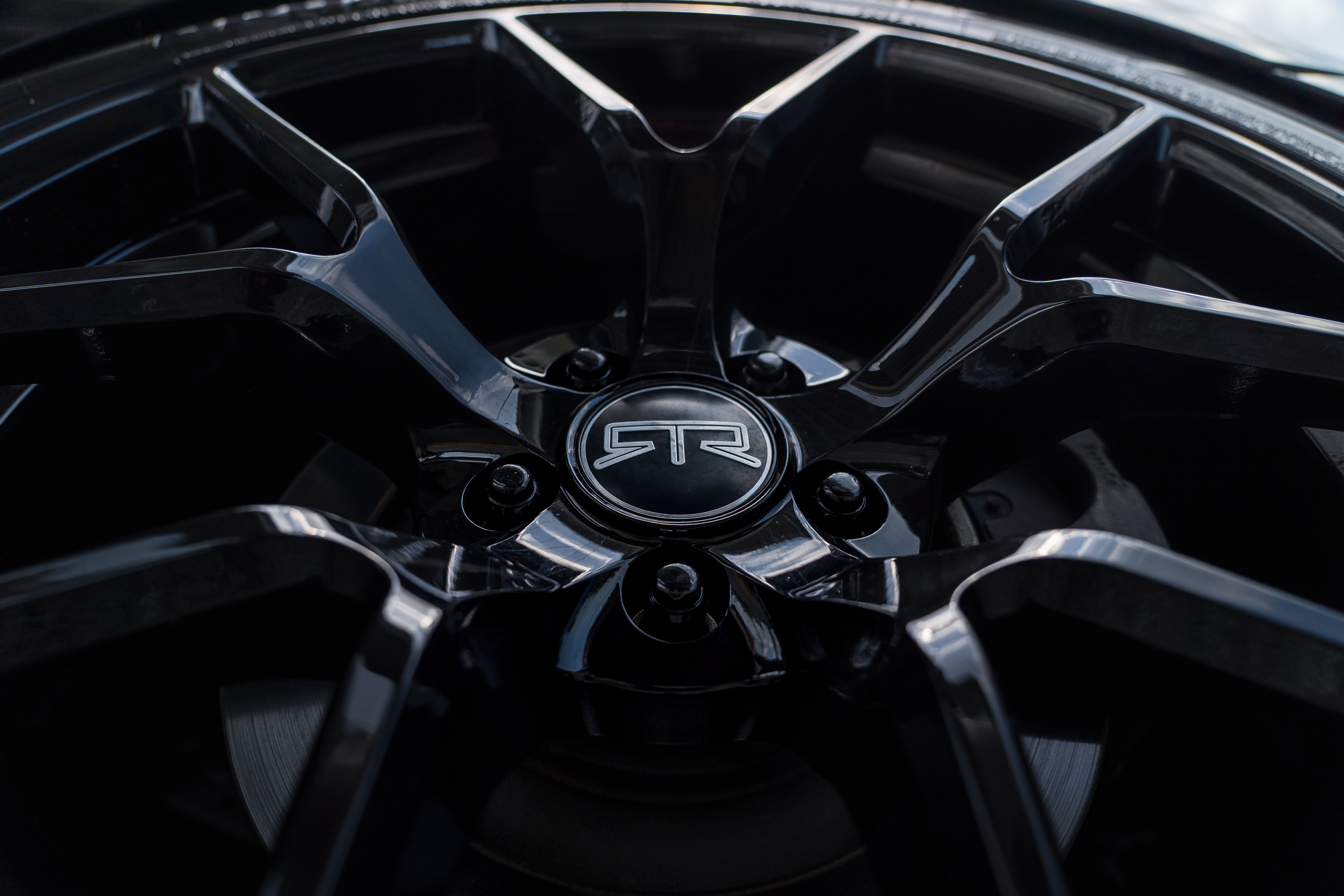 Detailed shot of a shiny black alloy wheel with reflective surfaces and intricate design.