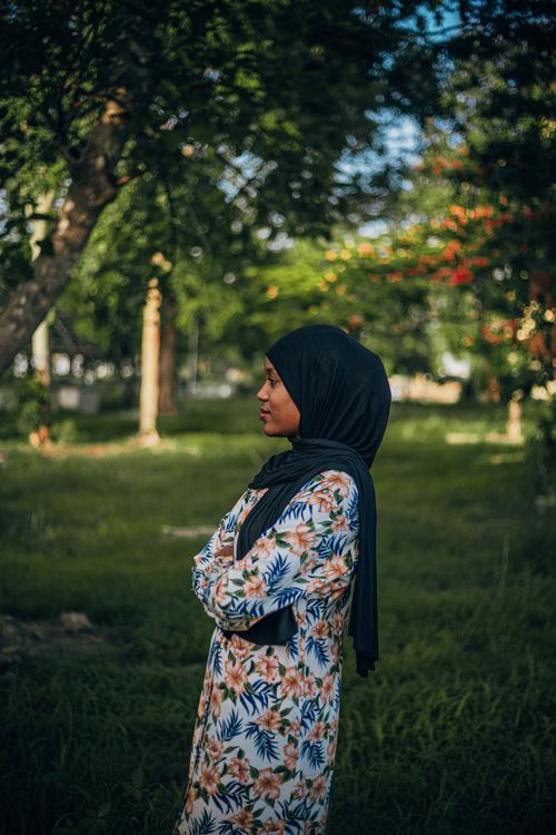 Free A serene outdoor portrait of a young woman in a hijab, set against lush greenery in a Nigerian park. Stock Photo