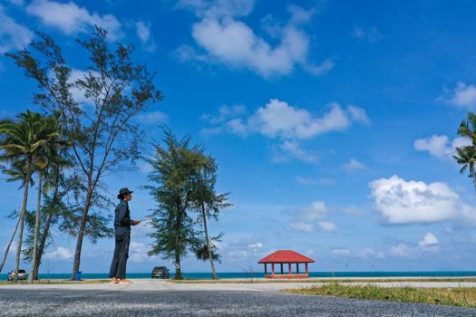 A serene beach view with palm trees and a gazebo under a clear blue sky in Permaisuri, Malaysia.