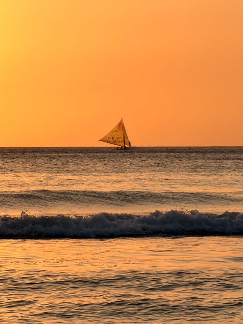 Free A sailboat drifts on calm seas at sunset near Boracay, Philippines. Tranquil and picturesque. Stock Photo