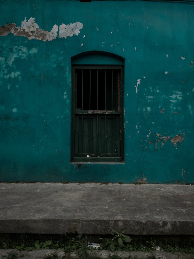 Facade Of Old House With Gloomy Window And Shabby Wall