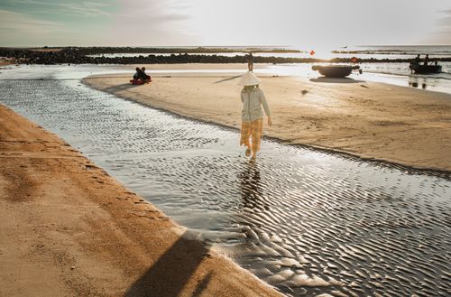 Free Woman walking along Cua Tung Beach in Vietnam during sunrise, capturing the serene coastal landscape. Stock Photo